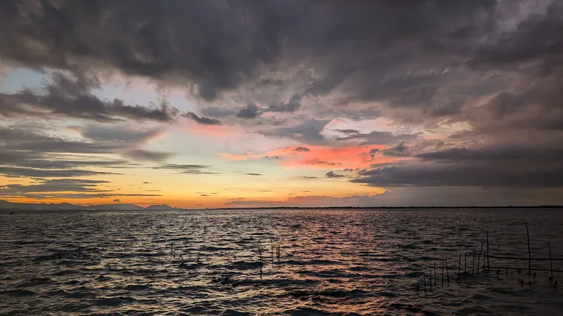 Heavy cloud over a lake with a narrow band of color near the horizon