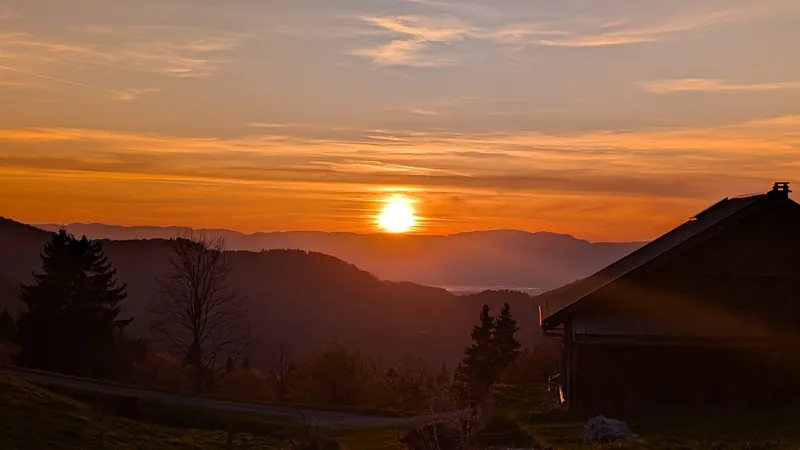 Thin high cloud glowing orange over a farmhouse silhouette